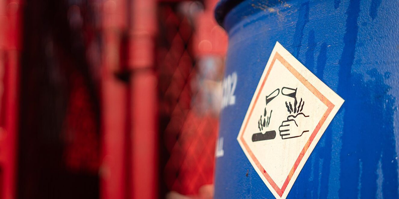 Blue barrel with corrosive warning label.